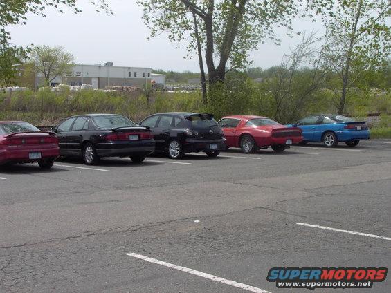 Several cars parked in a lot, including a red sports car and a blue coupe