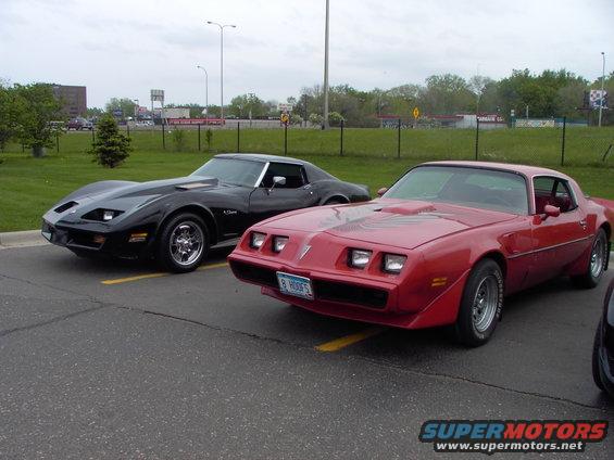 Red 1980s Pontiac Firebird with hood decal and black Chevrolet Corvette parked side-by-side