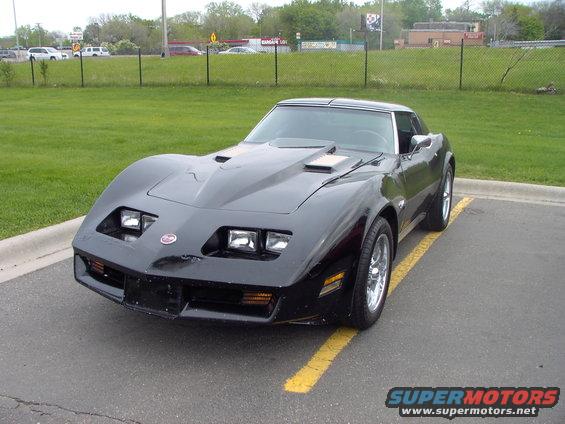 Black Chevrolet Corvette parked in a lot, hood scoops visible