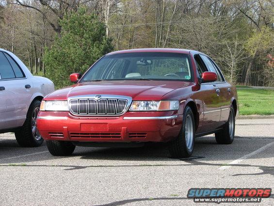 Red Mercury Grand Marquis parked next to a white car. Front view