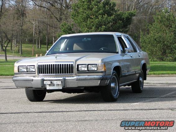 Silver 1980s Mercury Grand Marquis sedan parked on asphalt, front 3/4 view