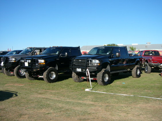 Black Ford F-250 Super Duty pickup truck with lifted suspension and large tires parked on grass