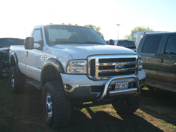 White Ford F-250 Super Duty pickup truck with large tires and a chrome bull bar