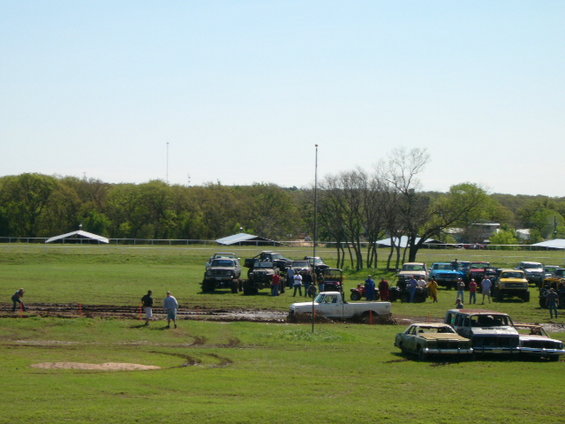 Mud bog event with many trucks and SUVs stuck in mud, people watching
