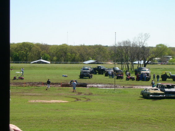 Mud pit scene with multiple off-road vehicles and people gathered