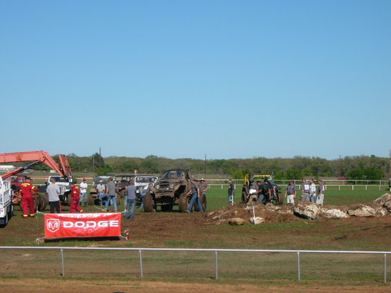Muddy off-road vehicles and people gathered near a Dodge banner