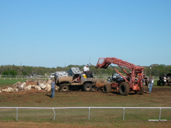 1978 Ford Bronco with camouflage wrap stuck on rocks, a tractor loader is next to it
