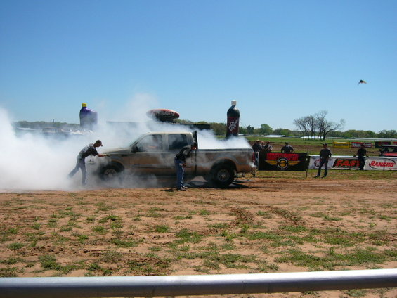 Tan Ford F-Series truck emitting smoke, two men near the front