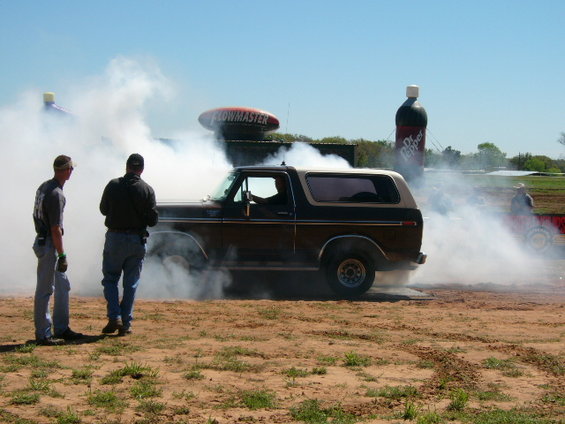Brown 1978 Ford Bronco doing a burnout with two men watching