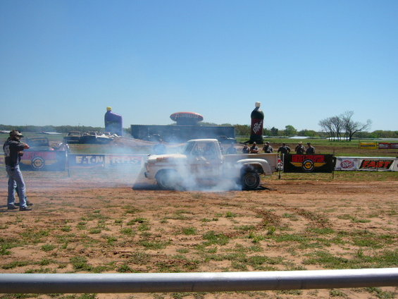 Pickup truck doing a burnout, emitting smoke. Text 'EATON' visible on a barrier