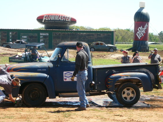 Side view of a blue 1953 Ford F-100 pickup truck with flames painted on the hood and bed