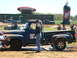 1978 Ford Bronco - A blue 1953 Ford F-100 pickup truck with flame decals is being worked on at an outdoor event, with a Dr. Pepper blimp in the background.