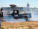 1978 Ford Bronco - A black pickup truck from the 1950s is seen performing a burnout, with smoke billowing around it.
