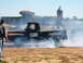 1978 Ford Bronco - A black pickup truck with flame decals performs a burnout, kicking up smoke at a drag strip event.