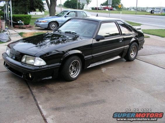 Black coupe parked on driveway, another car in background