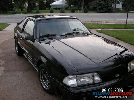 Black coupe parked on driveway, front 3/4 view. Visible watermarks include '06.06.2006' and 'SUPERMOTORS.NET'