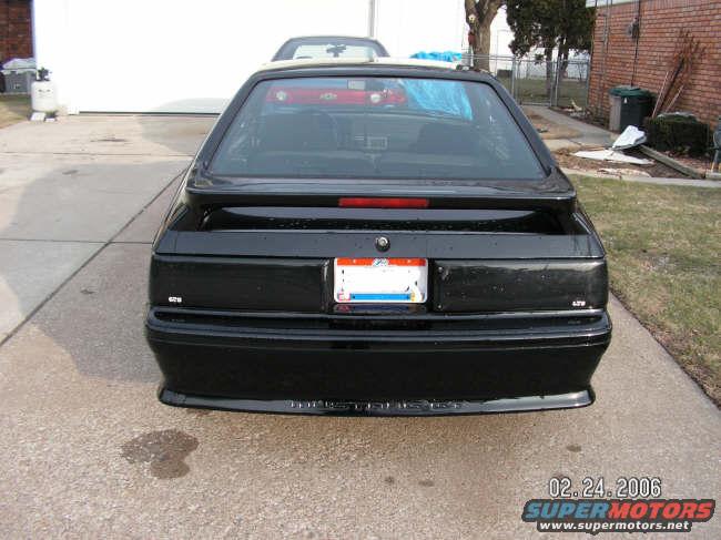 Rear view of a black 1988 Ford Mustang hatchback with a spoiler and a license plate