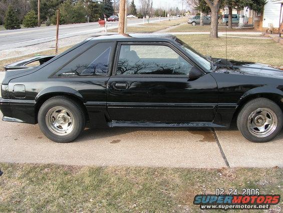 Black coupe car side view, parked on concrete driveway