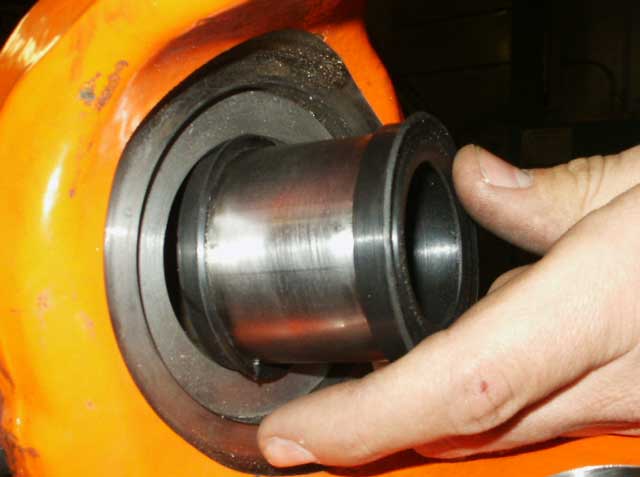 Hand installing a metal sleeve with black rings into an orange housing