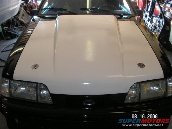Car front with a white hood scoop and black fenders. Has two hood pins