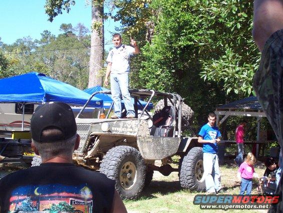 Off-road buggy with a man standing on top and another man leaning against it