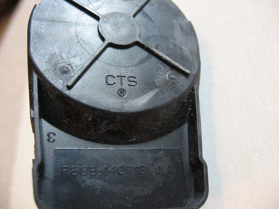 Black plastic automotive part with 'CTS' and 'F60B-14C078 AA' molded into it