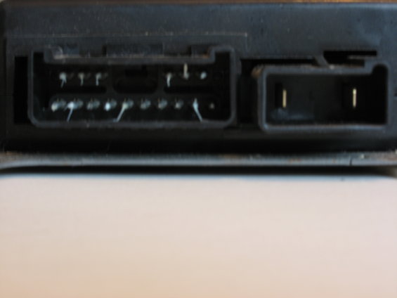 Close-up of two black plastic automotive electrical connectors with visible pins and some white residue