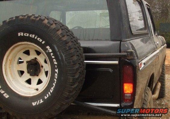 Rear view of a black Ford Bronco with a spare tire mounted on the back. Visible text on tire says 'Radial Mud-terrain T/A'