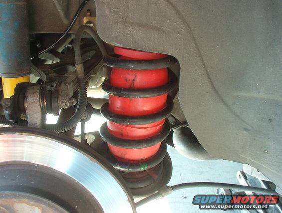 Rear suspension with red air springs, blue shock absorber, and brake rotor