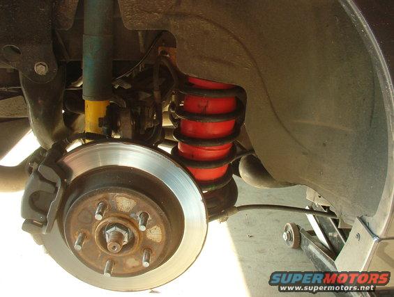 Rear suspension with red air springs and yellow shock absorber. Supermotors.net logo visible