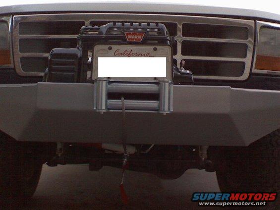 Front of a Ford truck with a WARN winch mounted on the aftermarket bumper. California license plate is visible
