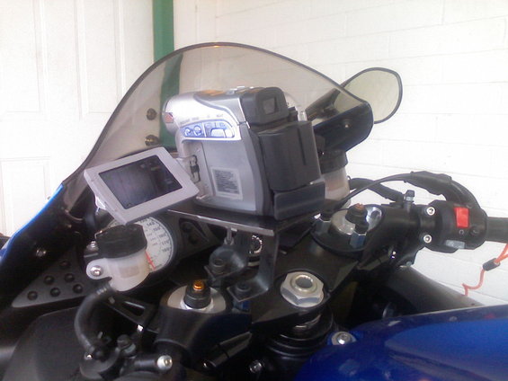Motorcycle dashboard with a video camera and GPS mounted. Speedometer visible