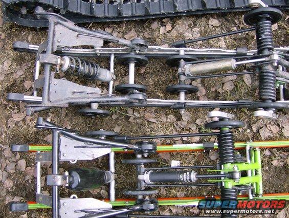 Close-up of snowmobile suspension components, including tracks, shocks, and wheels