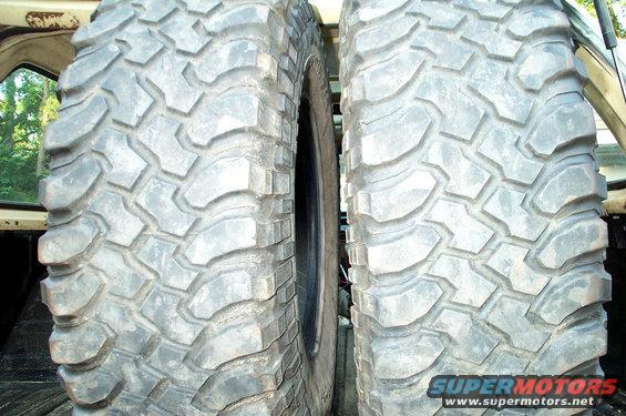 Two large off-road tires are side-by-side in the bed of a truck