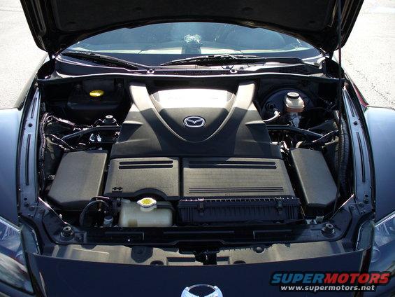 Mazda RX-8 engine bay with black plastic covers and a prominent Mazda logo