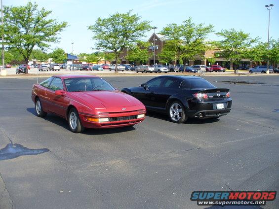 1991 Ford Probe parked next to a black Mazda RX-8 in a parking lot