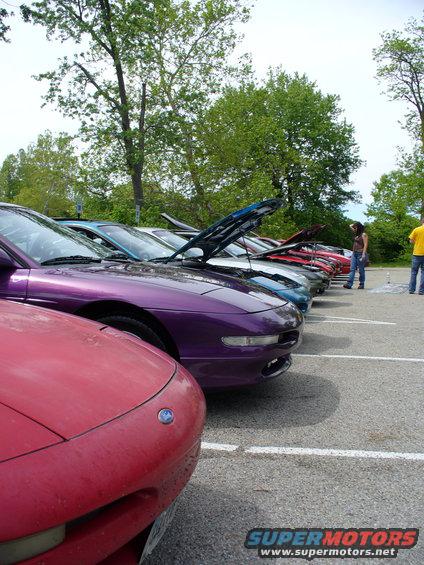 Line of 1991 Ford Probes parked, hoods open on some