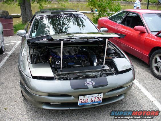 Silver 1991 Ford Probe with hood open, showing engine. Red Ford Probe parked next to it