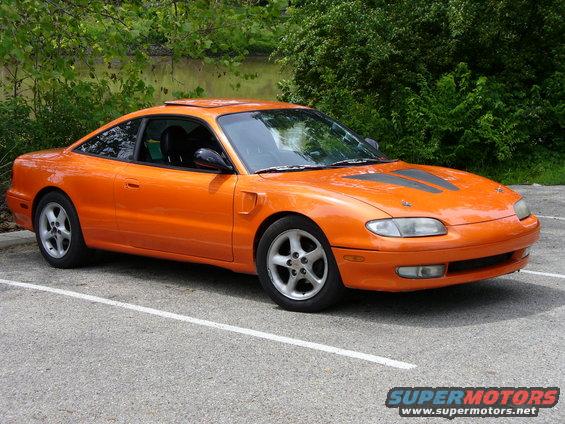 Orange sports coupe with black racing stripes on hood, parked