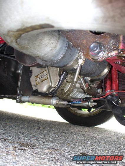 Close-up of turbocharger, exhaust pipe, and suspension components under a vehicle