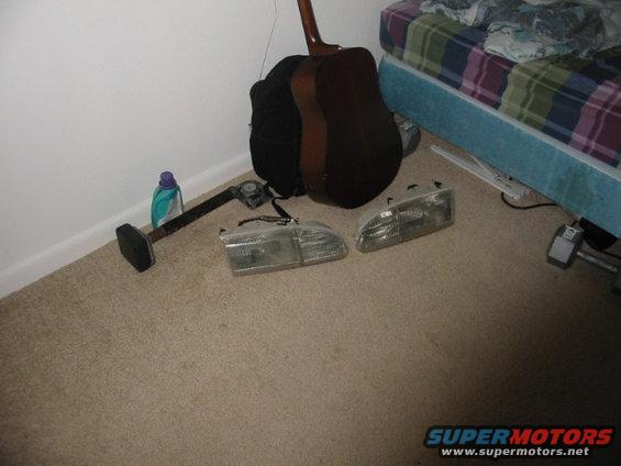 Two clear plastic car headlights with visible internal reflectors, lying on a carpeted floor