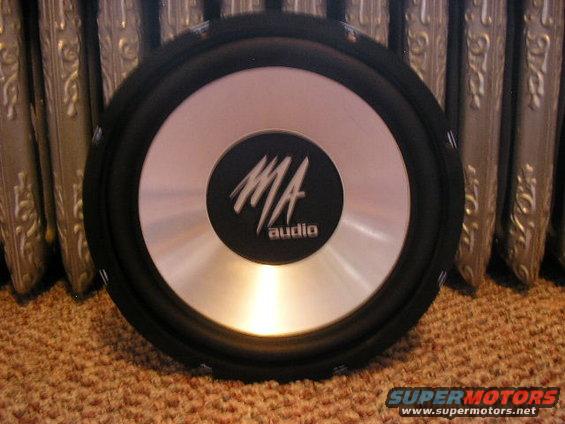 MA audio subwoofer with silver cone and black surround, resting on carpet