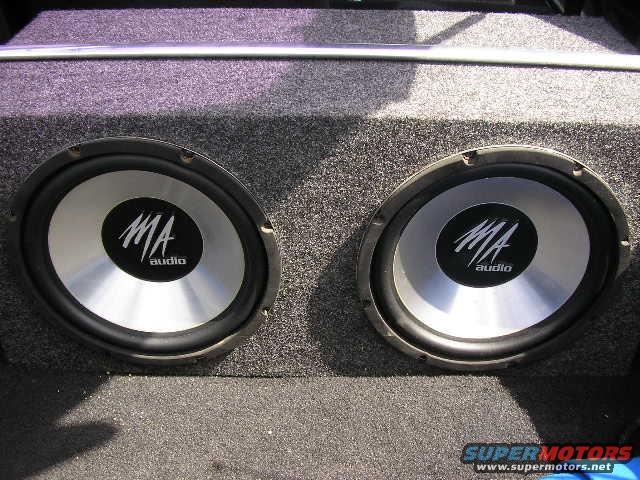 Dual MA audio subwoofers in a carpeted enclosure inside a vehicle's trunk