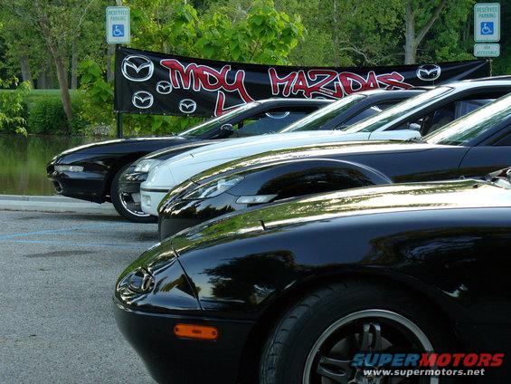 Several Mazda cars parked in a line, with a banner reading 'MDY MAZDAS' behind them
