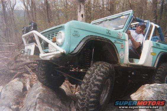 Light blue 1969 Ford Bronco on rocks, front 3/4 view. Off-road modifications visible