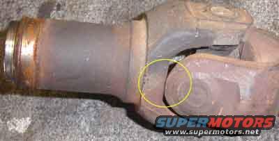 Close-up of a rusty driveshaft U-joint with a yellow circle highlighting wear