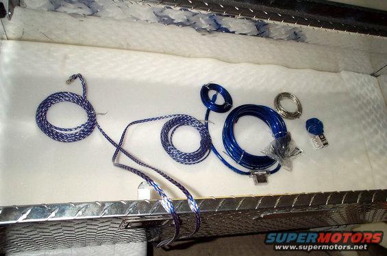 Wiring kits and accessories laid out on a white surface inside a metal-lined compartment
