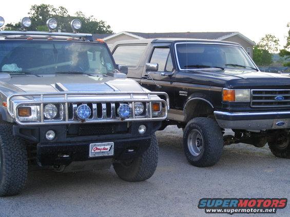 Black 1990 Ford Bronco pickup truck parked next to a silver SUV
