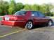 2000 Mercury Grand Marquis - A red sedan is shown from the rear quarter angle, parked in an asphalt lot with yellow lines.