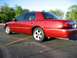 2000 Mercury Grand Marquis - A red sedan is parked in a lot under a clear sky with trees in the background.